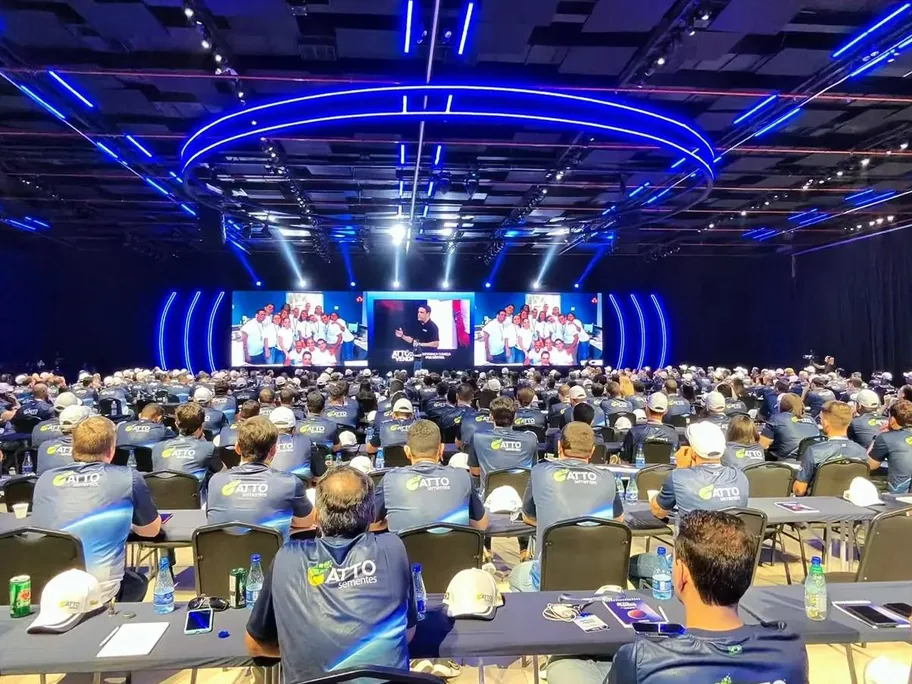 Auditório lotado na Convenção Atto, com telões e iluminação azul sobre o palco